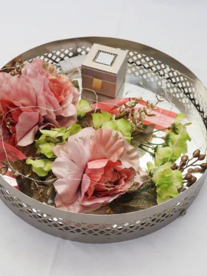 This simple yet elegant ring platter features a silver mesh tray decorated with pink flowers and a small box. It's a beautiful and understated option for presenting your engagement rings.