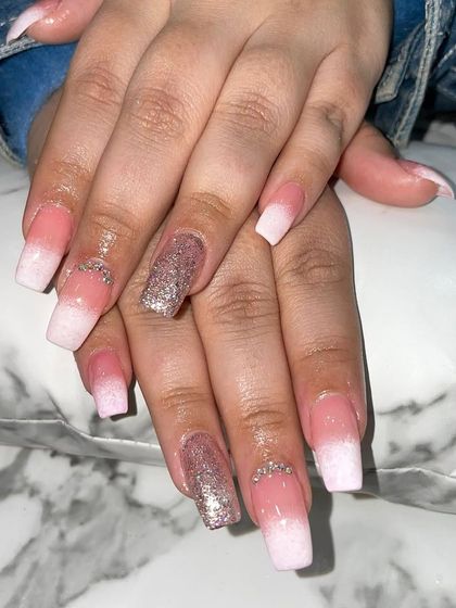 A classic pink and white ombre set on square nails, with a sparkling glitter accent nail.