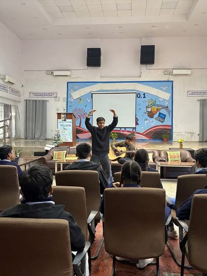 An instructor leads a warm-up exercise in a large hall, demonstrating the movements for the students. Our sessions are designed to be active and engaging, even in large spaces.