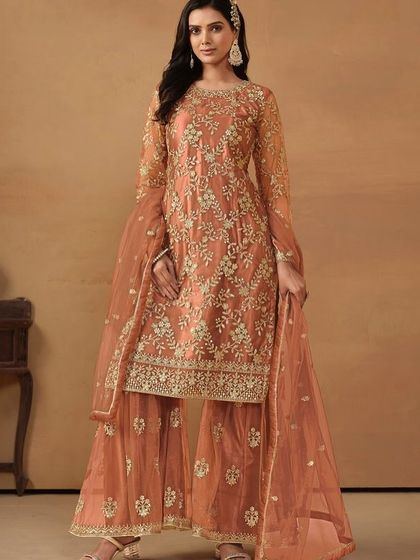 A beautiful dark salmon net suit with sharara pants. The delicate sequence work gives it a soft shimmer, perfect for a daytime wedding or festive gathering.