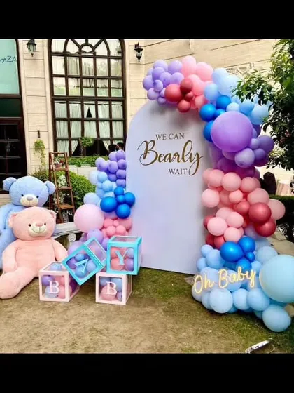 For this baby shower, I designed a "We Can Bearly Wait" theme with a beautiful balloon arch in shades of pink, purple, and blue. The setup includes large teddy bears and transparent "BABY" blocks filled with matching balloons.