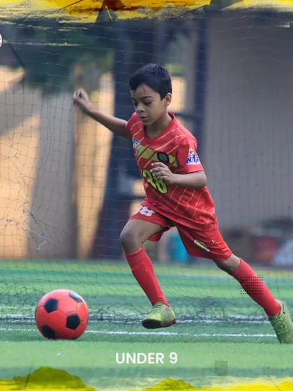 A U9 player strikes the ball during a friendly match, showing great form and technique.