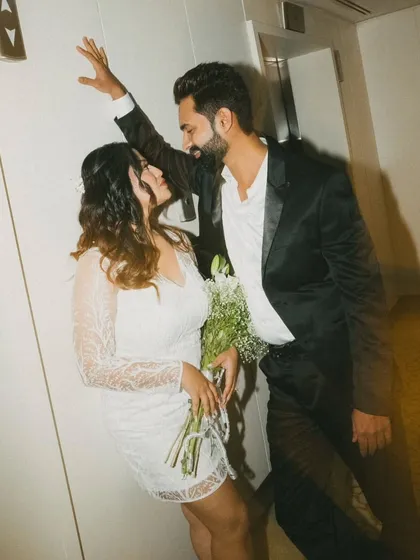 A playful and stylish indoor shot against an elevator door. This image has a cool, urban vibe, capturing a candid moment of interaction with a bit of film-like grain.