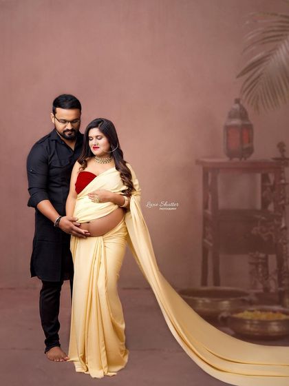 An intimate couple's portrait featuring the modern saree drape. The warm, earthy tones of the studio setup create a cozy and romantic atmosphere.