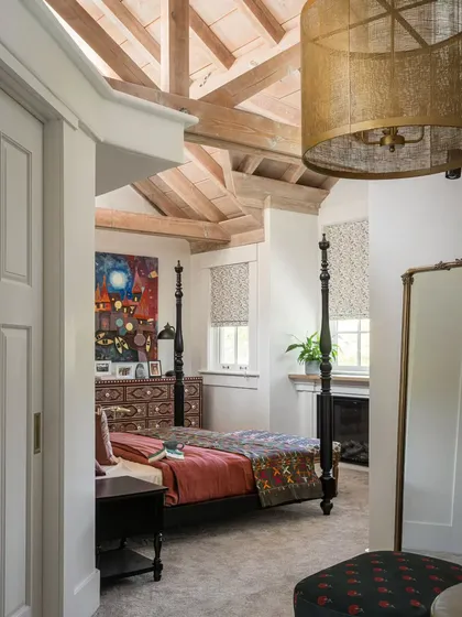 This tranquil bedroom in Saratoga features a stunning four-poster bed set against a backdrop of warm, neutral tones. The vaulted wooden ceiling and large window add to the room's airy and spacious feel, creating a perfect retreat.