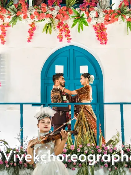 A beautiful varmala moment with a live violinist adding a touch of romance. The couple exchanges garlands on a balcony with Santorini-themed decor, creating a unique and picturesque setting.