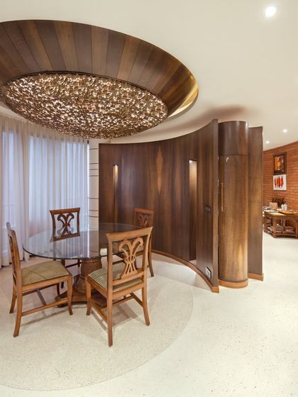 The dining area in the Outré House, where a stunning hemispherical ceiling detail with a custom 'Champa' lamp creates an intimate and dramatic focal point.
