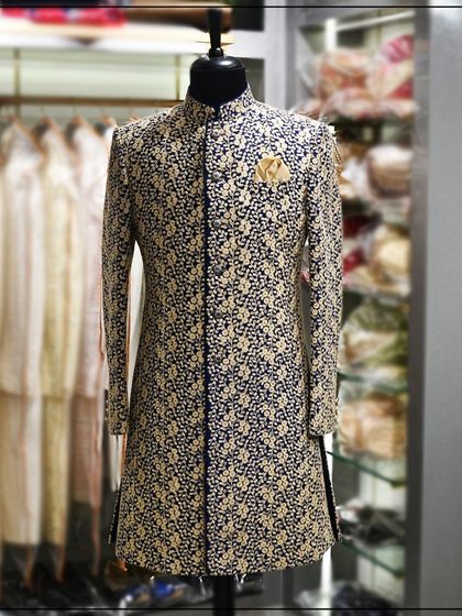 A full view of the navy blue Indo-Western sherwani with dense gold floral embroidery, showing its regal and opulent design.
