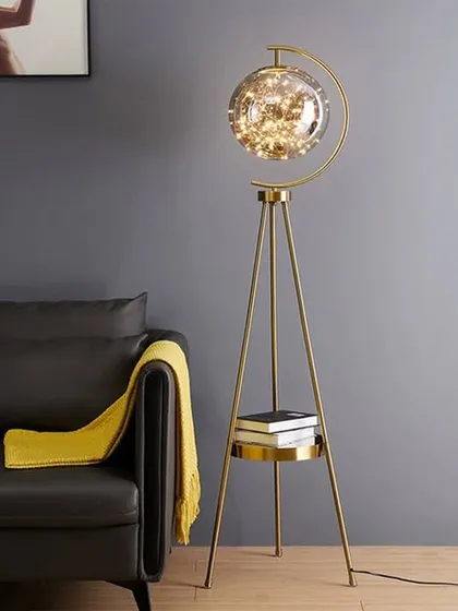 This tripod floor lamp is a perfect example of how we blend form and function. The antique brass finish, stable tripod base with a built-in shelf, and a glass globe filled with fairy lights make it a conversation starter that provides warm, ambient lighting.