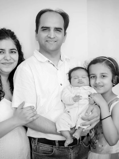 A complete family portrait in black and white, with parents, a proud big sister, and the sleeping newborn.