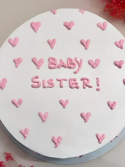 A top-down view of the 'Baby Sister' cake, showing the pattern of little pink hearts.