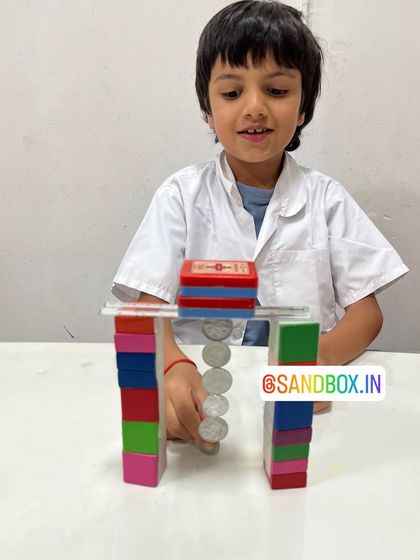 Success! This student smiles as he adds another coin to his floating chain. Each successful experiment builds confidence and a love for scientific discovery.