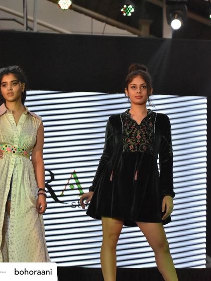 Our designs on the runway. This shot captures two of our looks: a sleeveless longline jacket on the left and an embroidered black velvet tunic dress on the right.