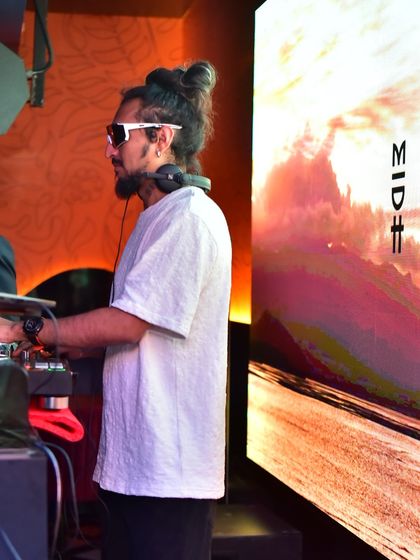 A side profile showing me focused on the mix, with abstract, colorful visuals creating a scenic backdrop on the LED screen.