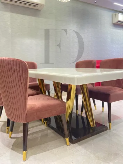 This dining set is perfect for a modern home, featuring a white onyx table with a sculptural gold base. The chairs, upholstered in a pleated rose-colored velvet, add a pop of color and texture.