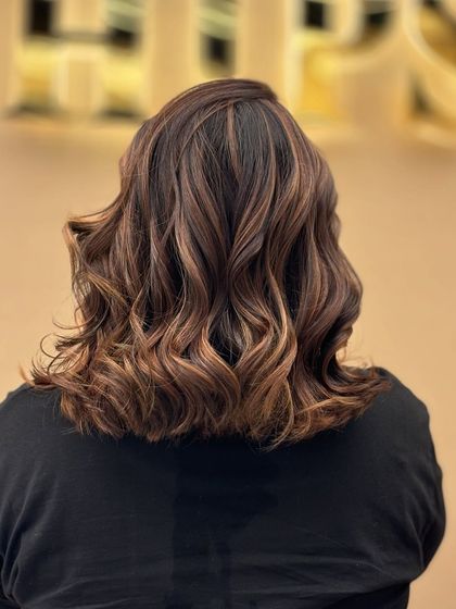 A back view of a client's hair with a beautiful blend of creative colors. The wavy style enhances the multi-tonal effect, creating a look that is both artistic and chic.