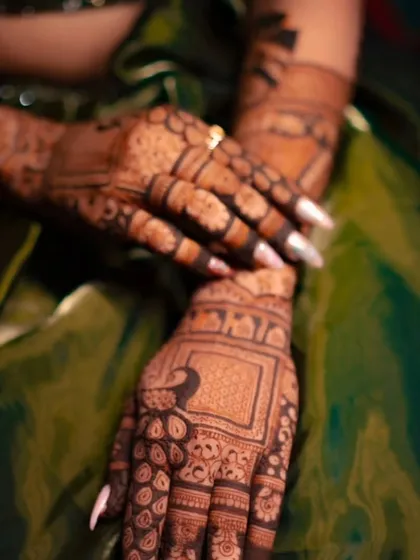 A close-up shot focusing on the detailed finger work and the peacock design on the back of the hand.