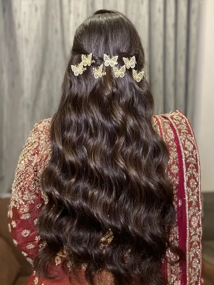 A beautiful shot of the bride's hairstyle. The soft waves are adorned with delicate butterfly clips, adding a touch of whimsy to her Sangeet look.