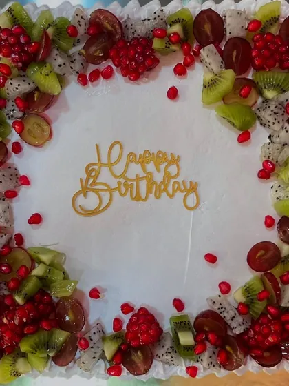 A square fresh fruit cake with a border of kiwi, dragon fruit, grapes, and pomegranate seeds.