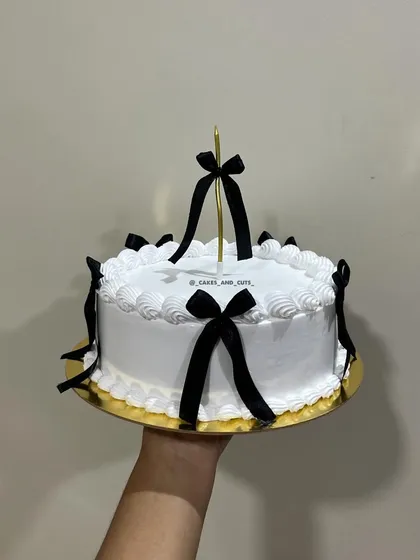 A hand-held shot of our vintage cake with black bows, showing the delicate piping work around the edges.