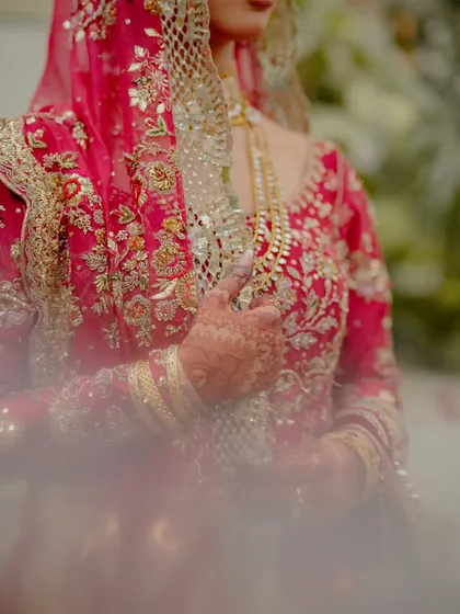 Every detail tells a story. This artistic shot focuses on the rich embroidery of the bride's attire and the beautiful henna design on her hand as she delicately holds her dupatta. It’s a tribute to the craftsmanship of her bridal look.