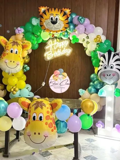 A jungle-themed first birthday with a balloon ring, neon sign, and large animal head foil balloons.