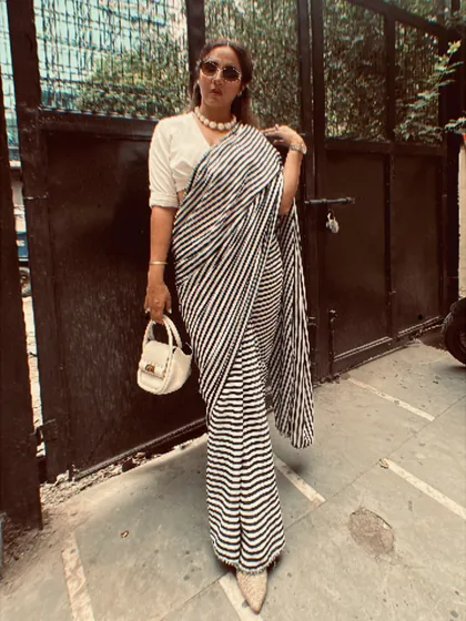 A full-length view of my modern saree look. Pairing the striped saree with a collared shirt-blouse, a statement pearl necklace, and a structured white bag creates a look that is both classic and contemporary.