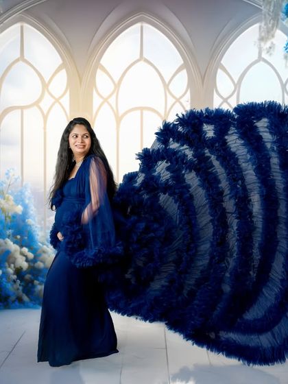 A fairytale moment in blue. This elaborate gown with a dramatic ruffled train creates a stunning visual against a dreamy, palatial backdrop for a fine-art maternity look.