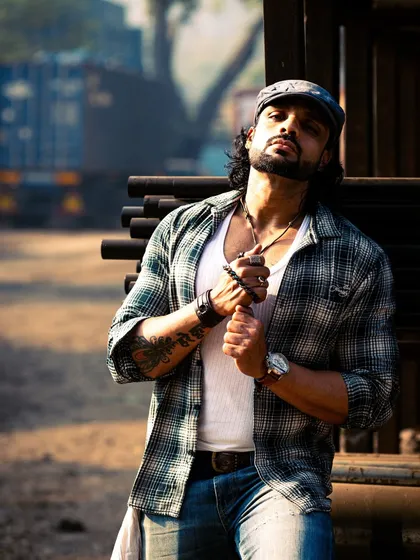This pose, with the tattoos visible, adds to the tough, artistic character of the portrait. The background of stacked pipes provides great texture.