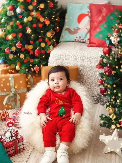 This little one is sitting patiently, surrounded by presents and Christmas trees. It's a perfect portrait to remember their very first holiday season.