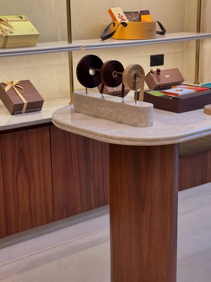 The finished custom-designed gifting and wrapping station at a chocolatier's retail store. The piece combines a marble top with a wooden base, demonstrating how we create functional furniture that aligns with a brand's luxury aesthetic.
