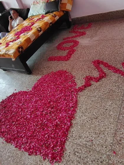 A close-up of the floor decor for a wedding surprise, with a large heart and the word 'Love' written with fresh rose petals.