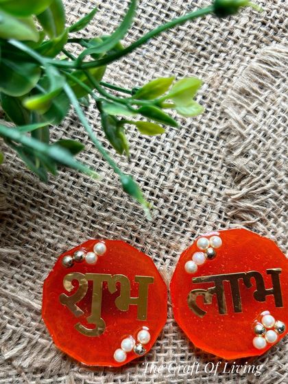 Simple and elegant red resin Shubh Labh discs with gold lettering and pearl accents. Perfect for a minimalist yet traditional festive look.