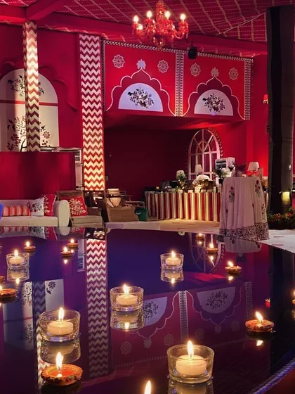 A beautiful detail from the 'Laal Ishq' event, where floating candles create reflections of love on a water surface. The background shows the rich red and white decor of the venue.
