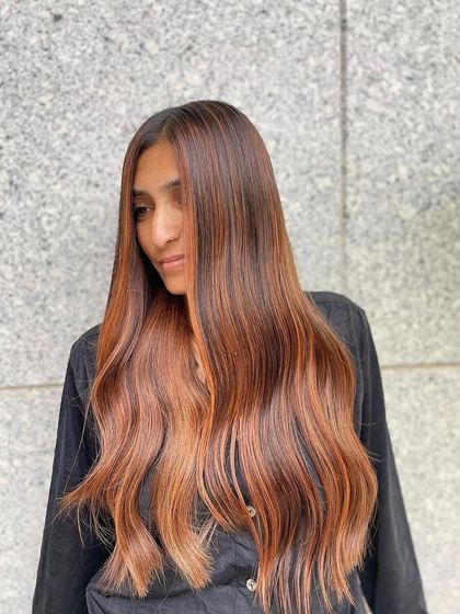This is a beautiful example of a copper balayage on long hair. The side view shows how the warm, fiery tones add vibrancy and radiance, perfectly complementing a warm skin tone.
