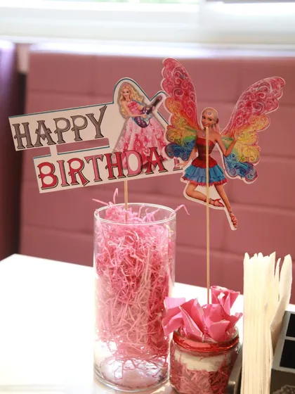 Themed table toppers are a small detail that makes a big difference. These Barbie cutouts add a fun, decorative touch to the dining tables.