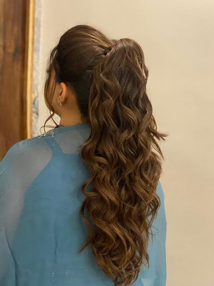 A messy tie look for a bridesmaid. This wavy, mid-height ponytail is stylish yet comfortable, allowing her to enjoy the wedding festivities.