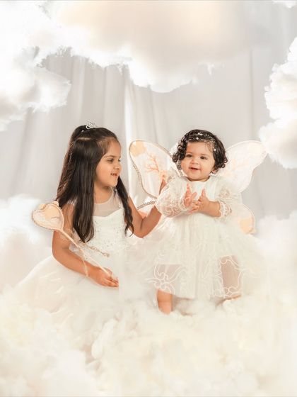Big sister joins the birthday girl for a magical photo in the clouds. Sibling shots during a first birthday session make the memories even more special.