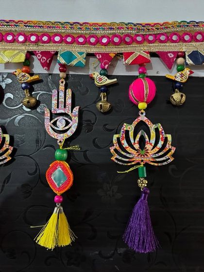 The beautiful textures and colors of the 'Shubh Toran', from the fabric pom-poms to the shiny tassels and wooden beads.
