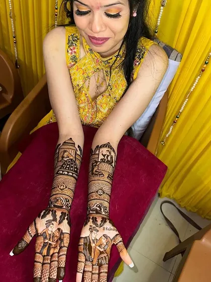 A happy bride showing her full figurative mehandi, which tells the story of her wedding through various scenes on her hands and arms.