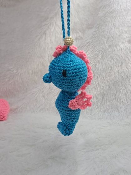 A closer look at the blue and pink seahorse hanging charm. The bright colors and cute shape make it a fun and eye-catching decoration.