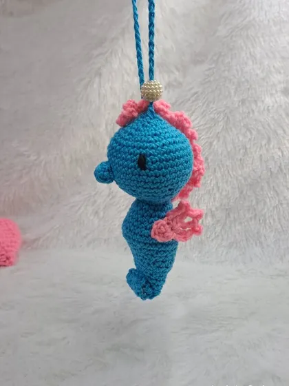 This adorable seahorse ornament is made in bright blue and pink, with a detailed, curly tail and fins.