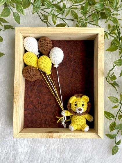 A sweet lion cub holding yellow, brown, and white balloons. This framed art is a unique way to decorate a jungle-themed nursery.