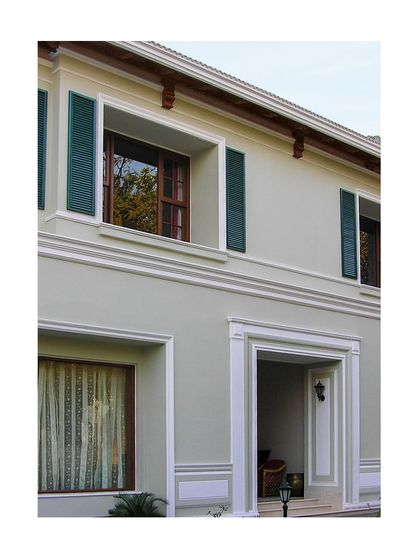 The recessed entrance and symmetrical window placements are hallmarks of the neo-classical style that inspired this design, creating a feeling of order and refined grace.