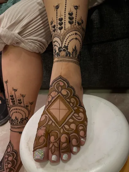 A modern and chic foot design, with a large central motif on the foot and a delicate pattern extending up the leg like a piece of jewelry.