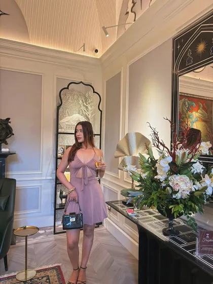 Holding a glass of wine in the elegant mini dress, a perfect look for a sophisticated party.