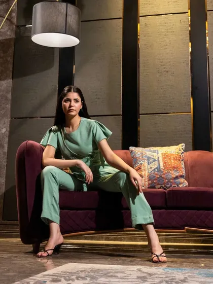 A model seated on a luxurious sofa in a mint green co-ord set. This lifestyle-oriented studio shot helps customers imagine wearing the outfit in a sophisticated, real-world setting.