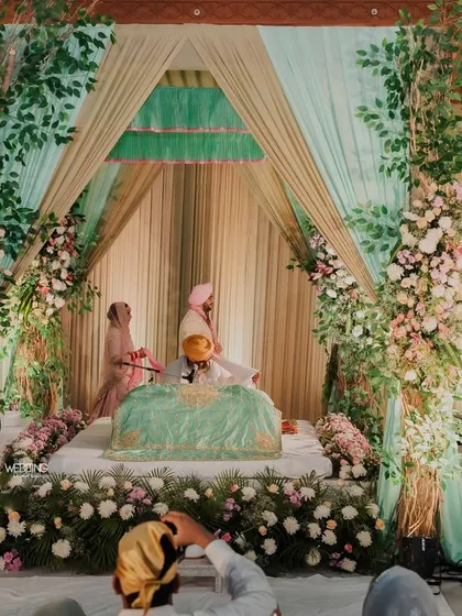A beautiful Anand Karaj setup. We used soft drapes in mint green and gold, with floral pillars to create a serene and respectful space for the Sikh wedding ceremony.