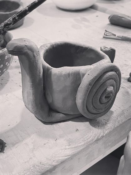 A whimsical snail-shaped pot, made using a combination of pinching and coiling techniques.