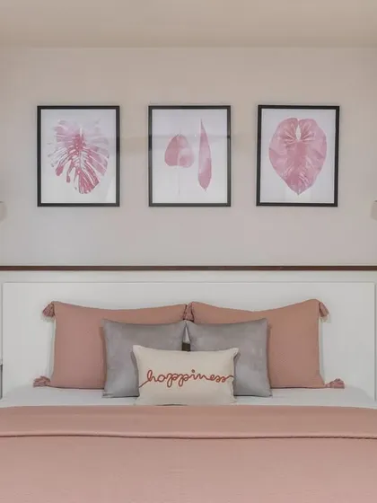 The guest bedroom is a serene retreat adorned in soothing pink hues. Oversized artwork above the bed adds sophistication, while soft pendant lights gently illuminate the space.